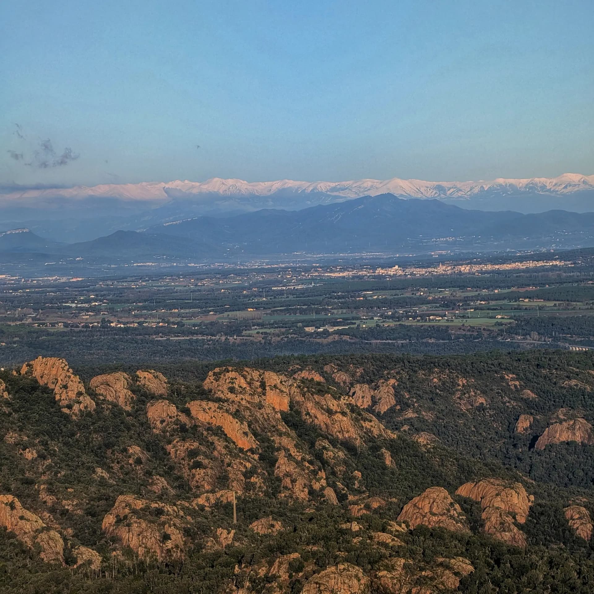 Panoramic view of the Pyrenees from Puig de les Cols, featuring peaks like Balandrau, Pic del Freser, and Costabona.