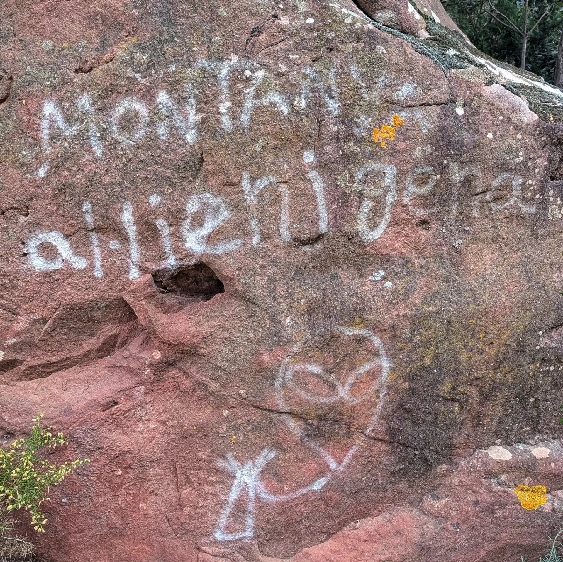 Grafit blanc de 'MONTAÑA alienígena' i un dibuix d'extraterrestre sobre una roca de Buntsandstein rogenca.