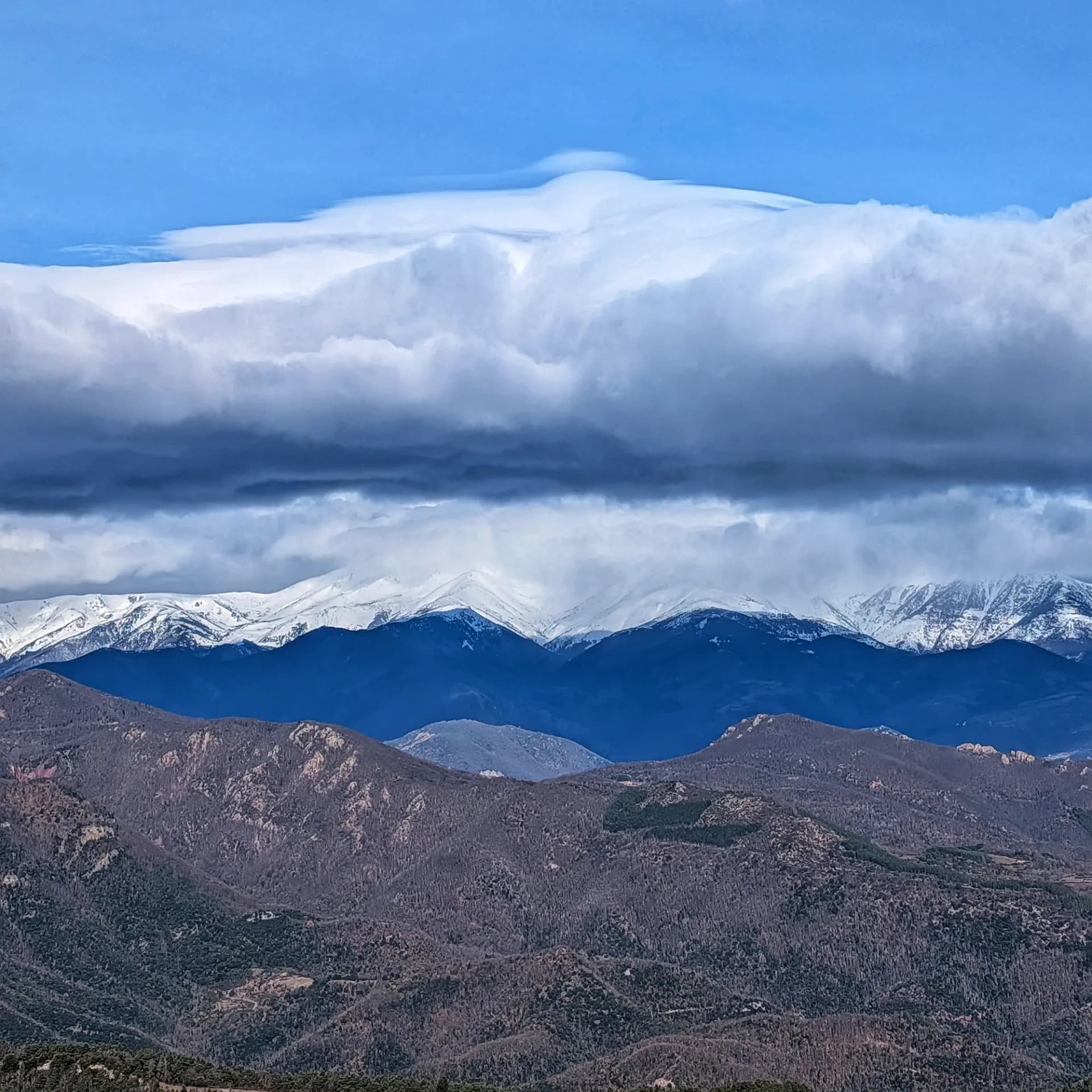 Canigó mountain with its peak partially covered by clouds, viewed from the Bassegoda summit.