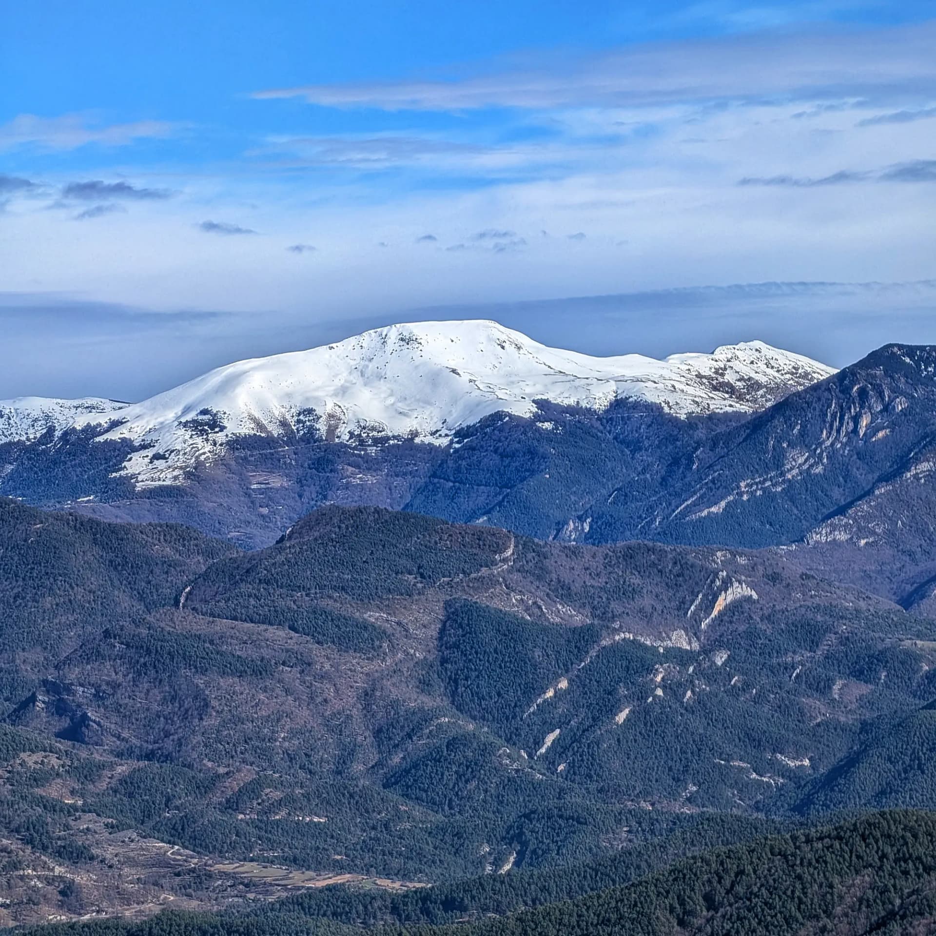 View of Taga and Puig Estela mountains from Pedró de Tubau summit under clear sky.