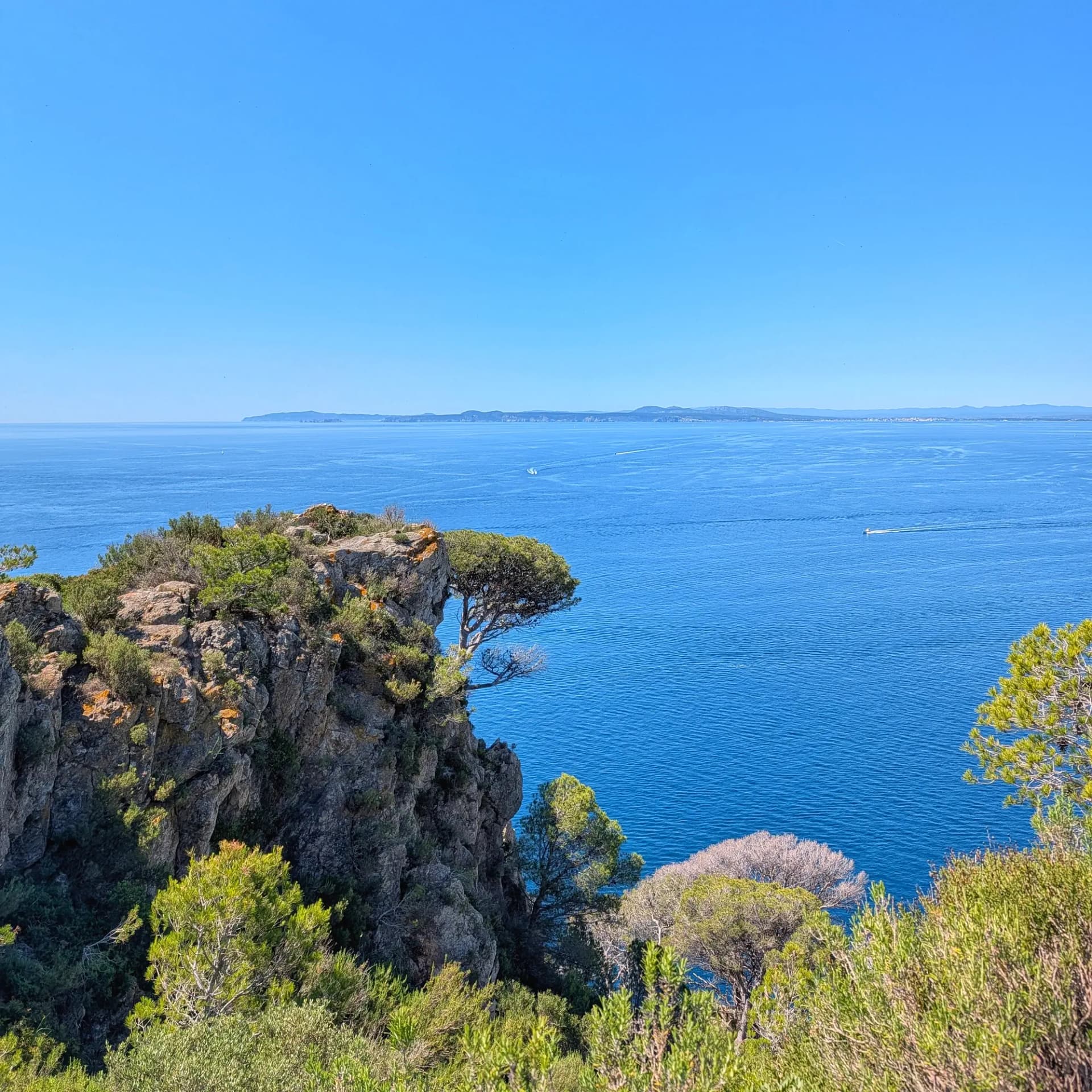 Vista panoràmica del mar Mediterrani des del Cap Norfeu, amb penya-segats rocosos i el massís del Montgrí a l'horitzó.