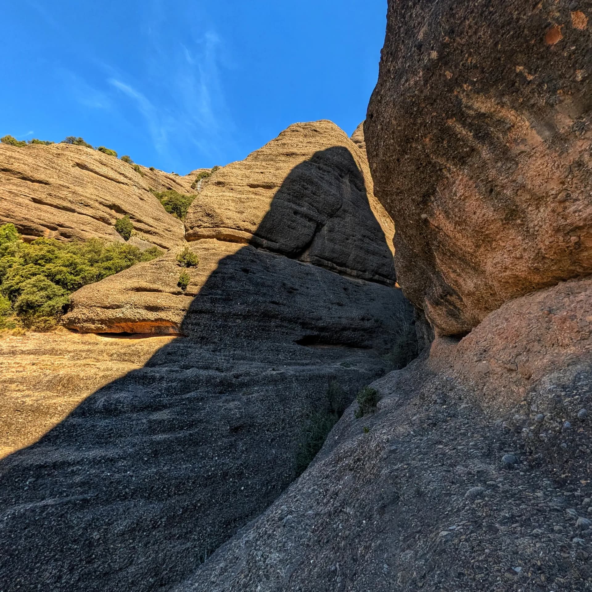 Formacions rocoses escarpades amb ombres profundes sota un cel blau clar als Barrancs de Sant Honorat.