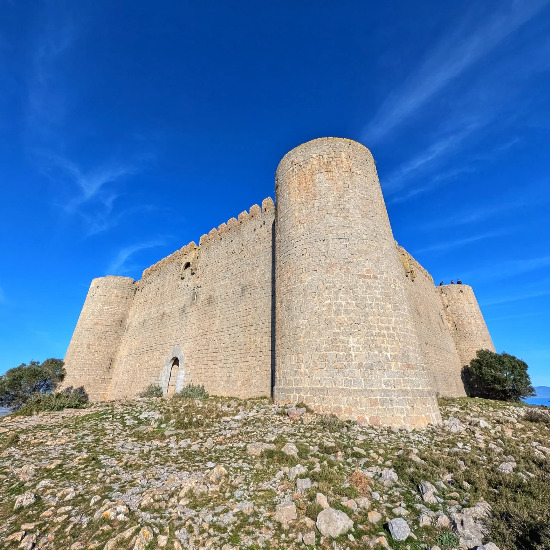 Castell de Montgrí, amb murs de pedra i torres rodones, sobre un cim rocós sota cel blau clar.