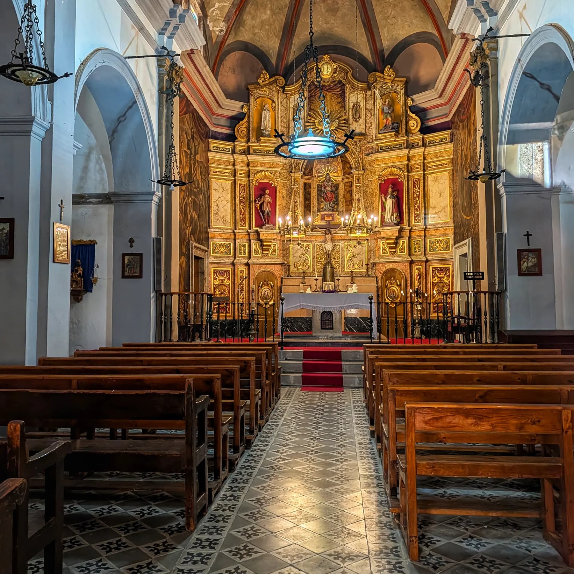 Interior de l'Església de Sant Bartomeu, l'Argentera, amb retaule daurat, bancs de fusta i sostre amb voltes.