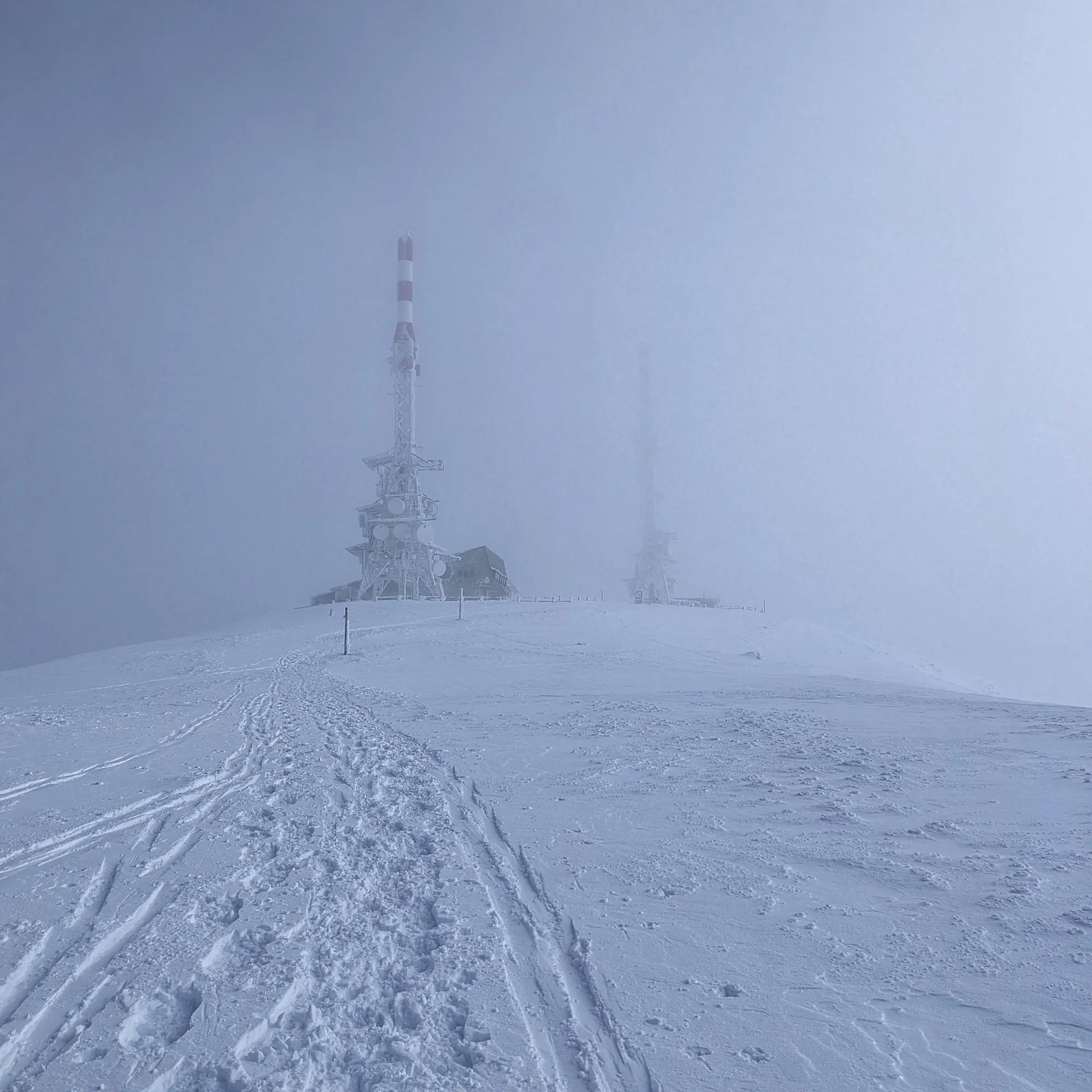 Cim nevat de la Torreta de l'Orri, envoltat de boira amb torres de comunicació poc visibles.