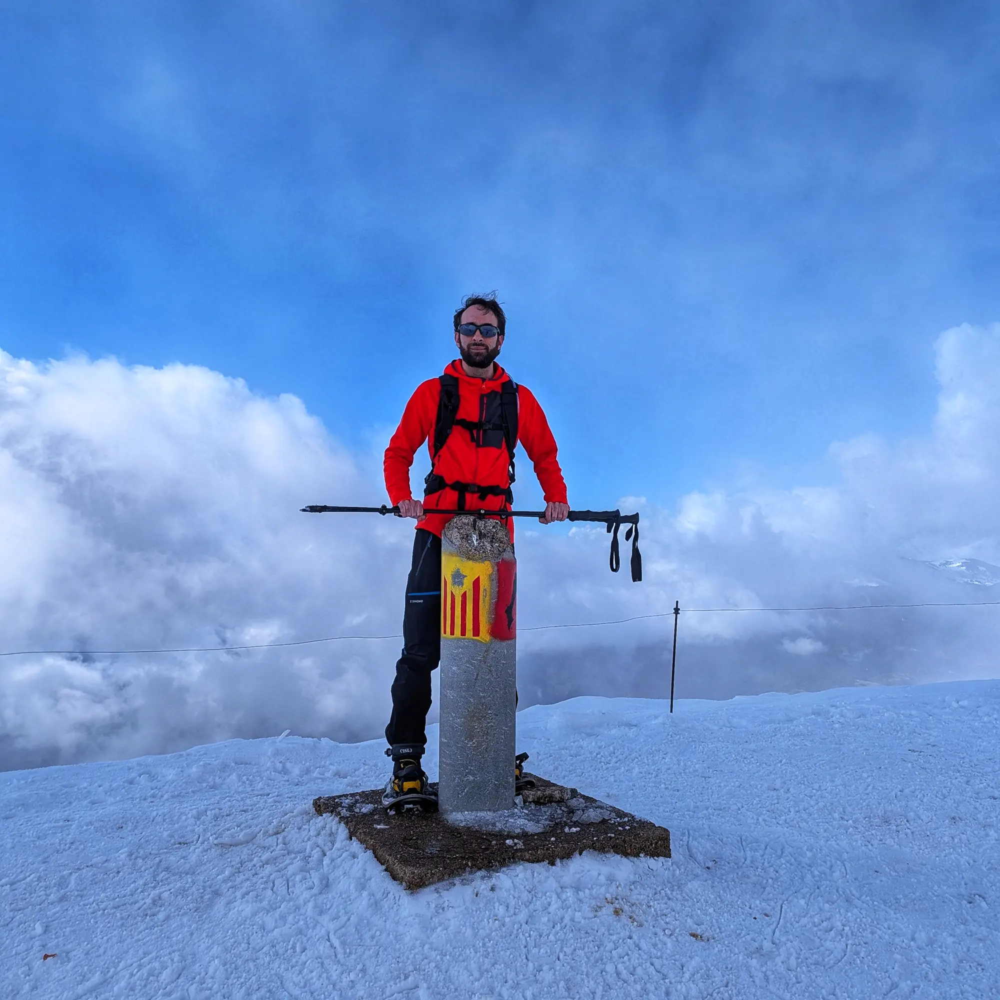 Cim del Taga nevat amb un tros de cel blau entre els núvols.