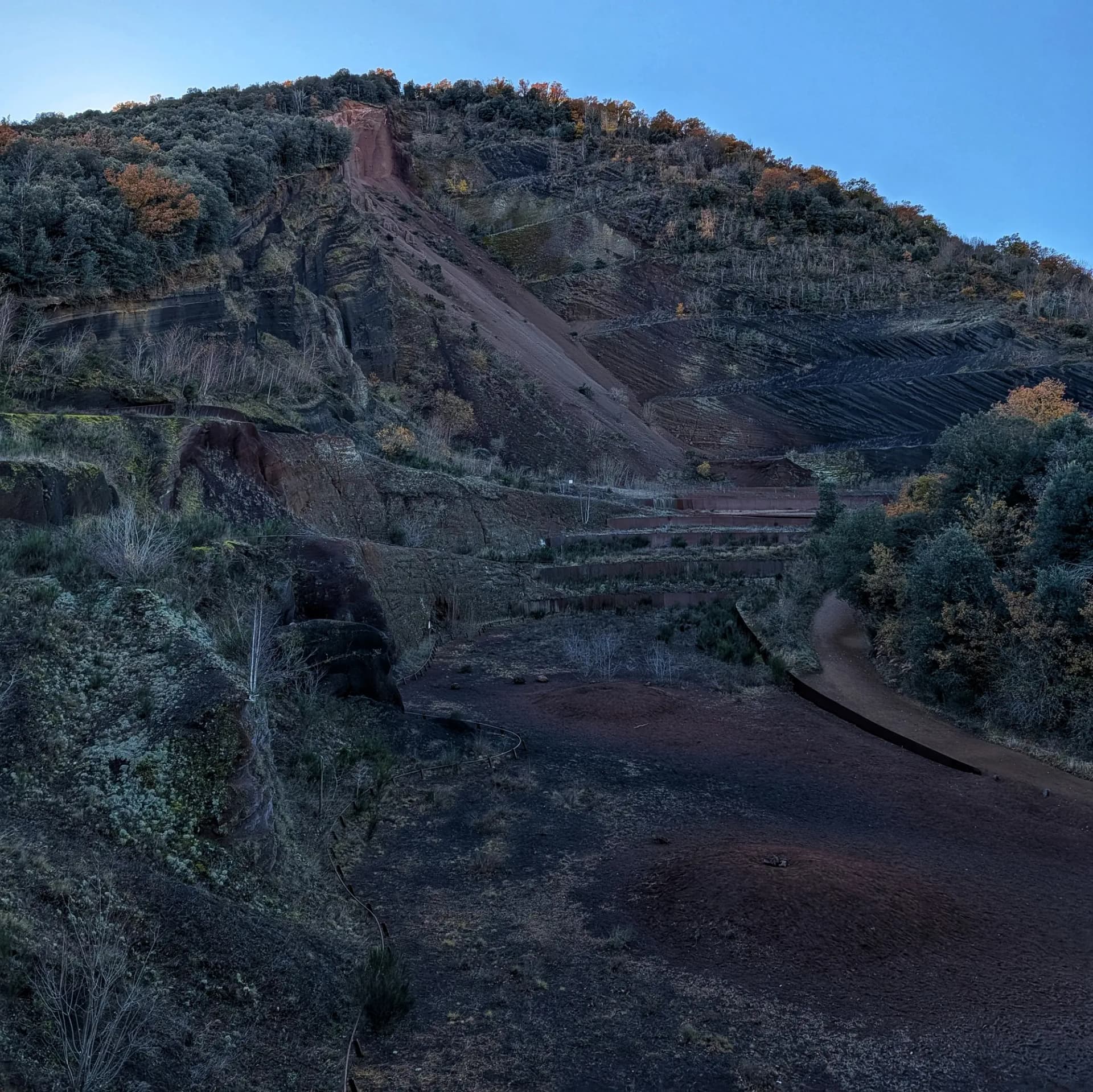 Visió de les grederes del volcà del Croscat, formades per fragments de roca volcànica. Grederes vermelloses del volcà del Croscat amb vegetació dispersa.