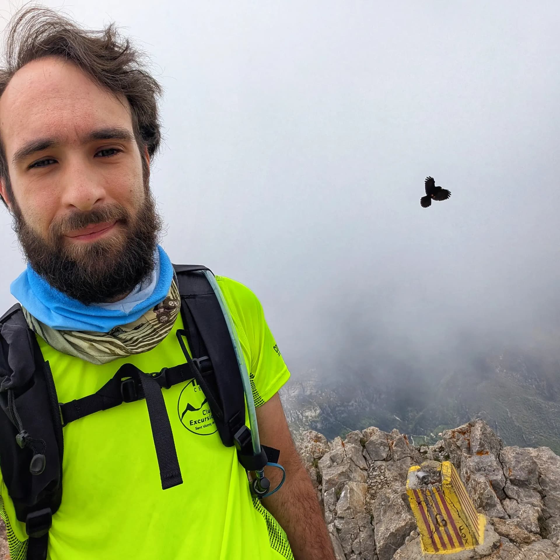 Cim del Pollegó Superior del Pedraforca, envoltat de boira, amb un ocell volant en la distància i un senyal de fita amb els colors de la senyera catalana. Cim del Pollegó Superior del Pedraforca, envoltat de boira, amb un ocell volant en la distància i un senyal de fita amb els colors de la senyera catalana.