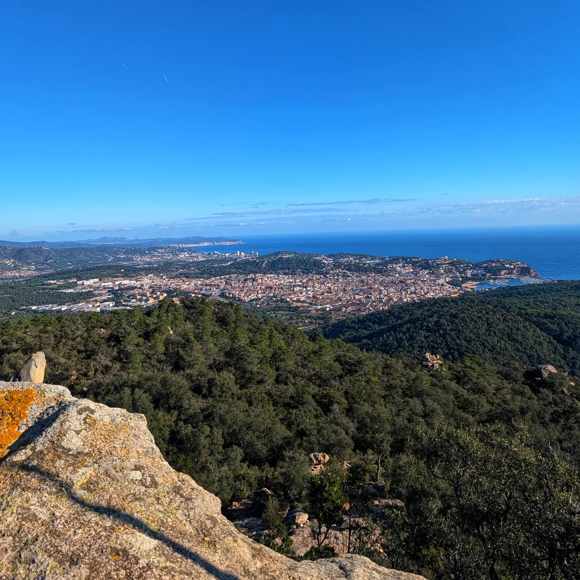 Vista panoràmica de Sant Feliu de Guíxols, mostrant la ciutat costanera, els seus edificis i el port, capturada des del cim del Puig Gros. Panoràmica de Sant Feliu de Guíxols amb costa, edificis i port des del Puig Gros.