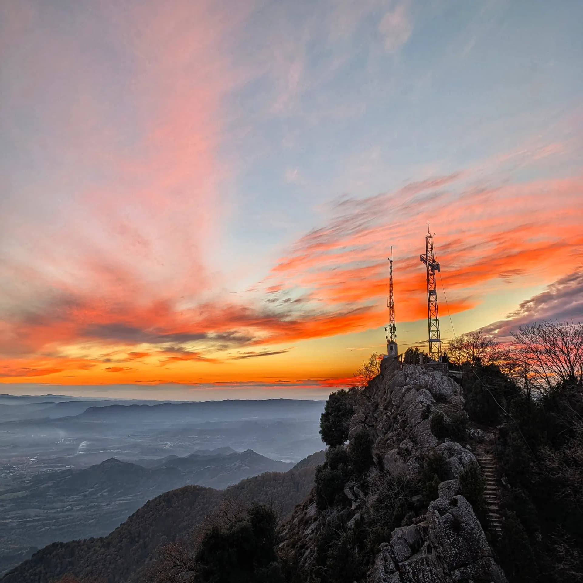 Vista de la posta de sol des del cim de Bellmunt, amb els colors càlids del cel il·luminant el paisatge. Posta de sol al cim de Bellmunt.