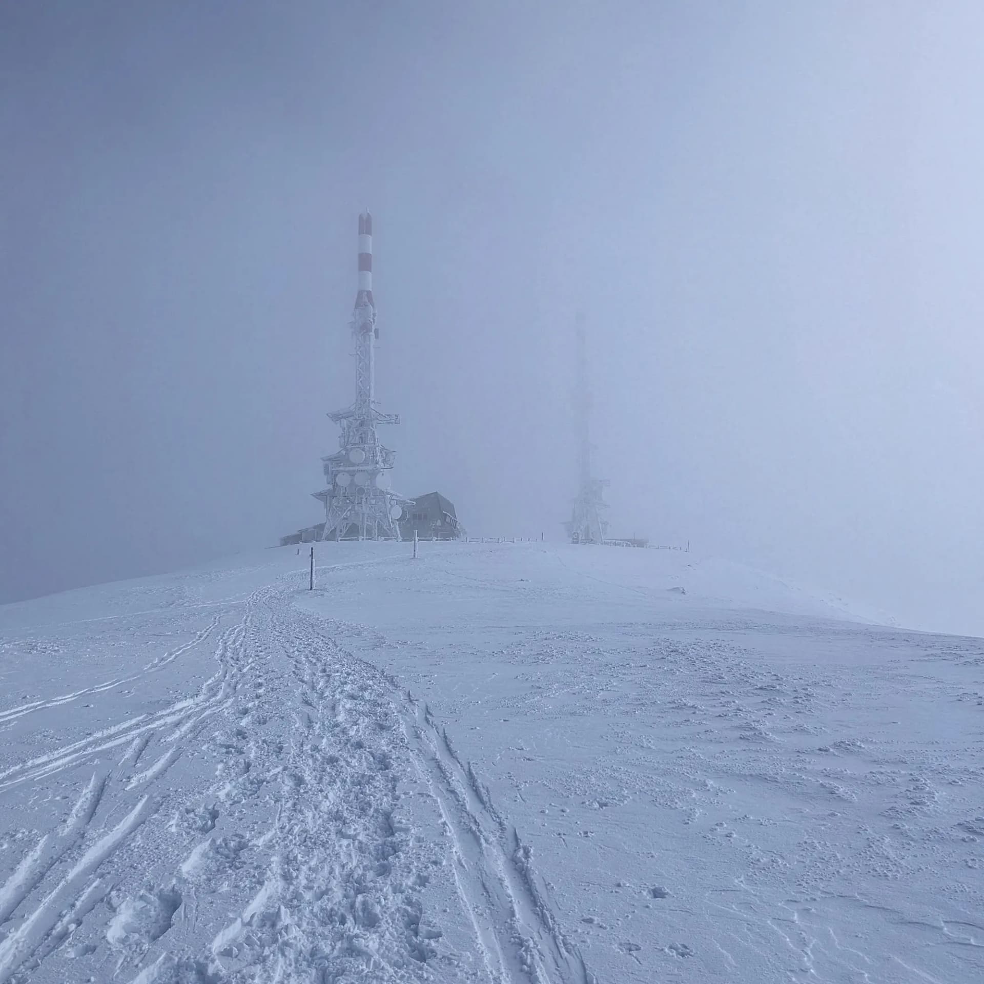 El cim de la Torreta de l'Orri, cobert de neu i envoltat de boira. Les torres de comunicació característiques de la muntanya són amb prou feines visibles. Cim nevat de la Torreta de l'Orri, envoltat de boira amb torres de comunicació poc visibles.