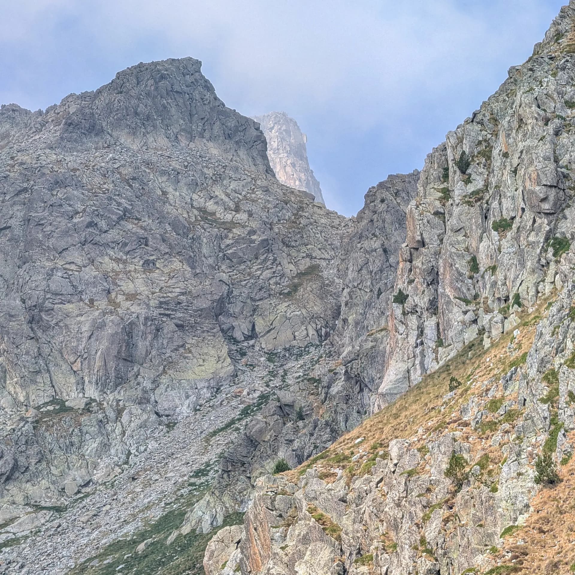 Ruta d'ascensió al Pic de Comaloforno i Besiberri Sud, iniciant-se a la Presa de Cavallers. El camí travessa tarteres de granit abans d'arribar als cims, amb descens passant pels estanys. Paisatge muntanyenc rocós amb pendents escarpats, tarteres de blocs i un pic llunyà parcialment amagat entre els núvols.